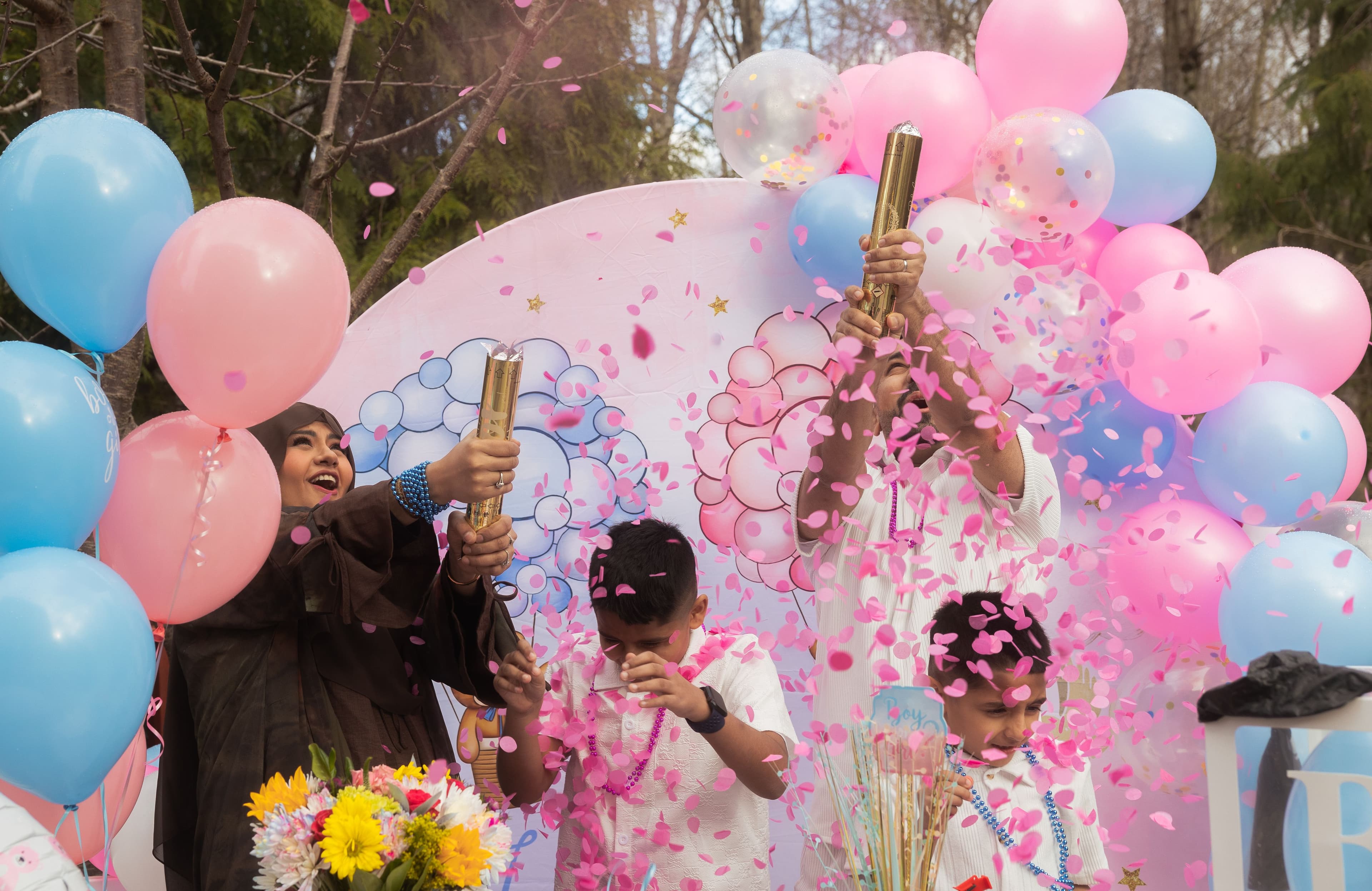 Family popping pink confetti at a gender reveal party